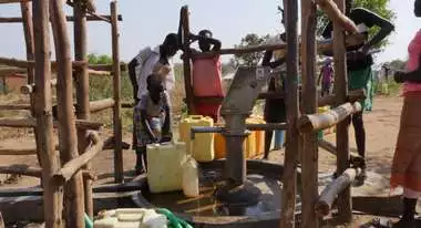 Menschen füllen an einem Brunnen Wasser ab
